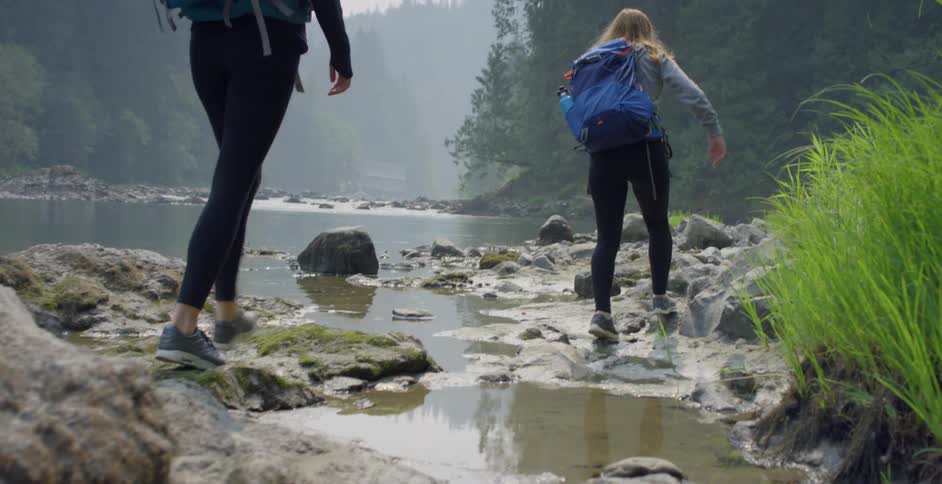 Two white women walk on a rivers shore