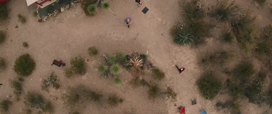 Three people wander around a campsite in a rural area