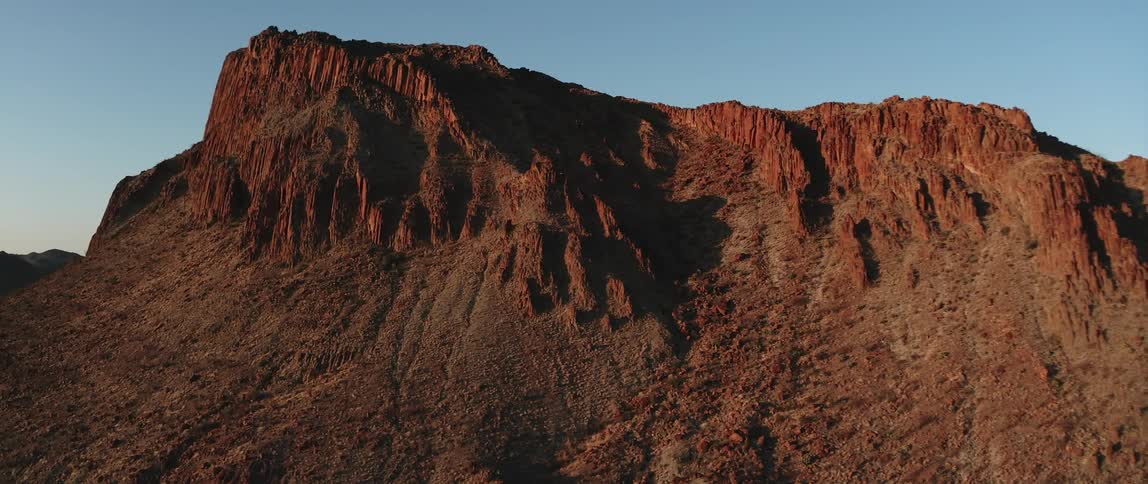 The sky is clear over the tall mountain
