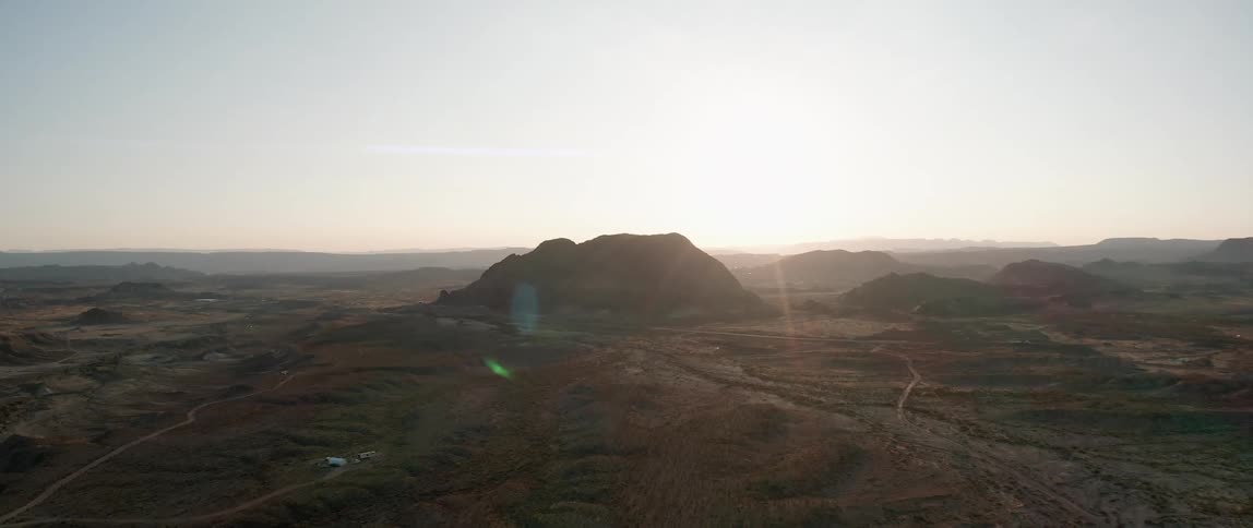 Encampment sits near mountain as sun brightens horizon