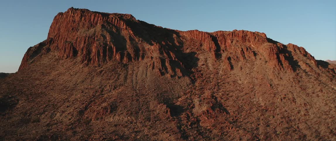 A rocky cliff with the sky and clouds in the background
