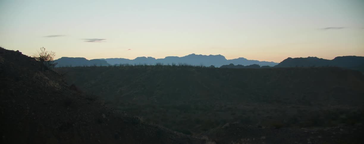 Hilly terrain gives way to a wide valley in a desert