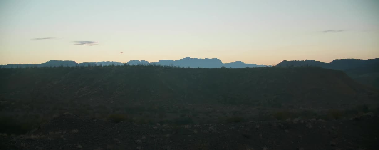 Sunset over the distant mountains on the desert badlands