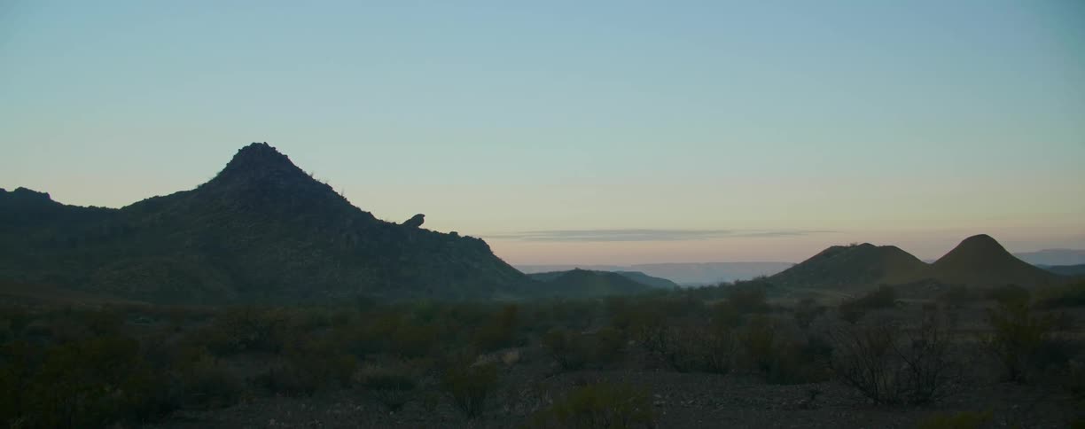 A desert with mountains the sky and clouds in the background