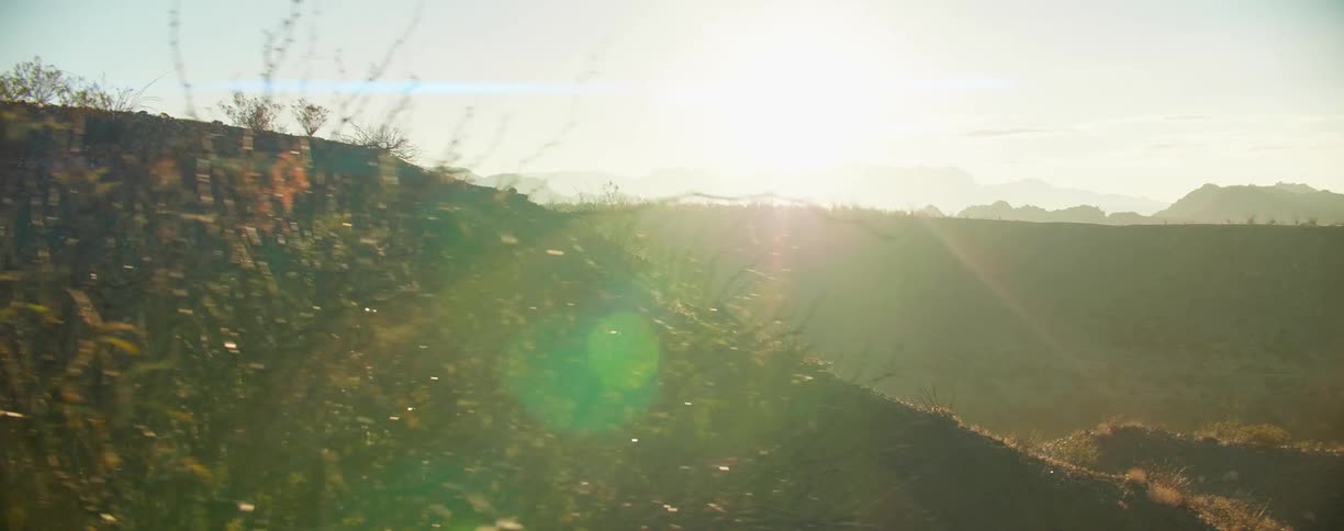 The sunlight shining down on a hilly countryside under a clear sky