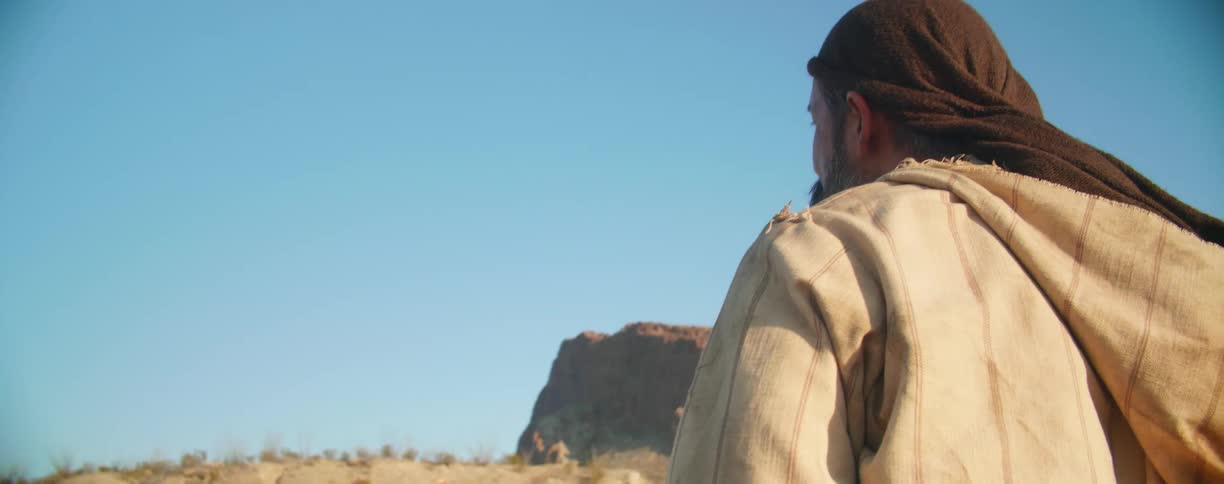 A man stands up from a leaning position while stopped in the desert