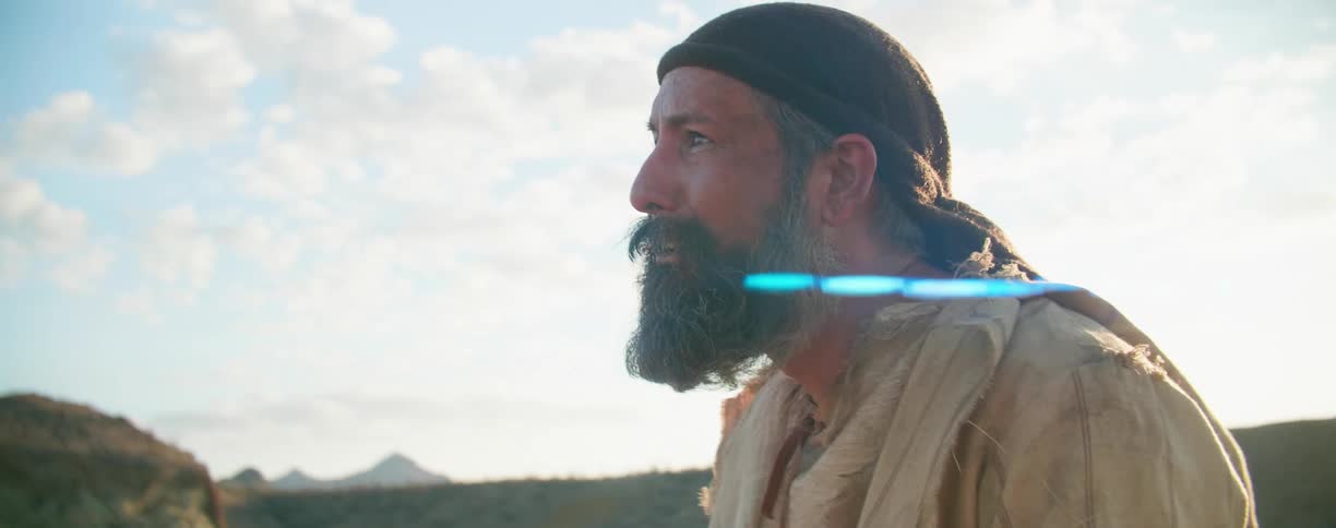 A man stands in a hilly area and looks off in to the distance