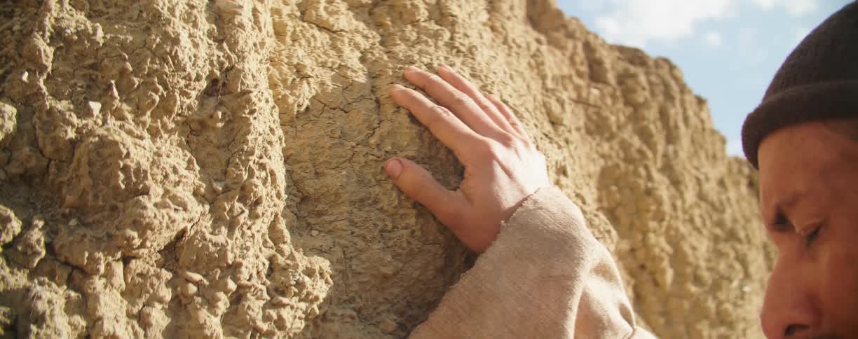 A man with his eyes closed rests his hand on a canyon