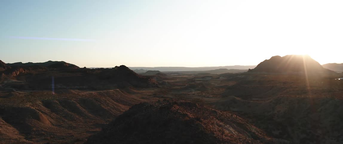 The sun illuminates a rocky valley in a desert