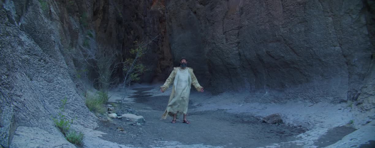 A man stands at the base of a canyon and prays