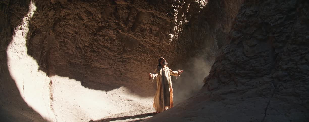 A man stands in the canyon raising his arms up