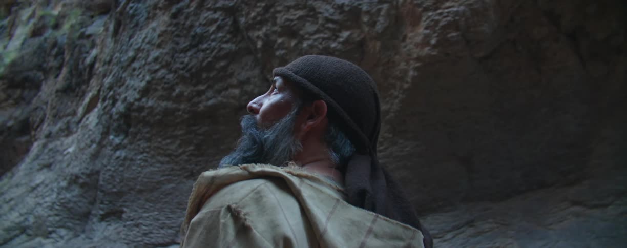 A man with a bandana and a coat walking in a canyon