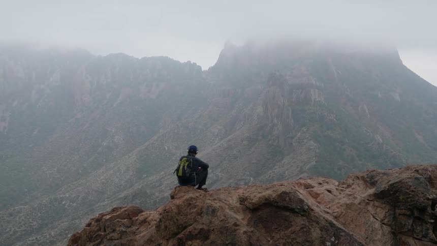 A man is sitting on a mountain outdoors