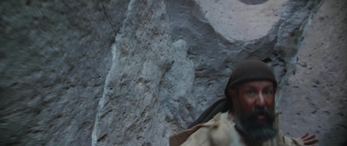 A man backing up in the corner of a canyon in fear