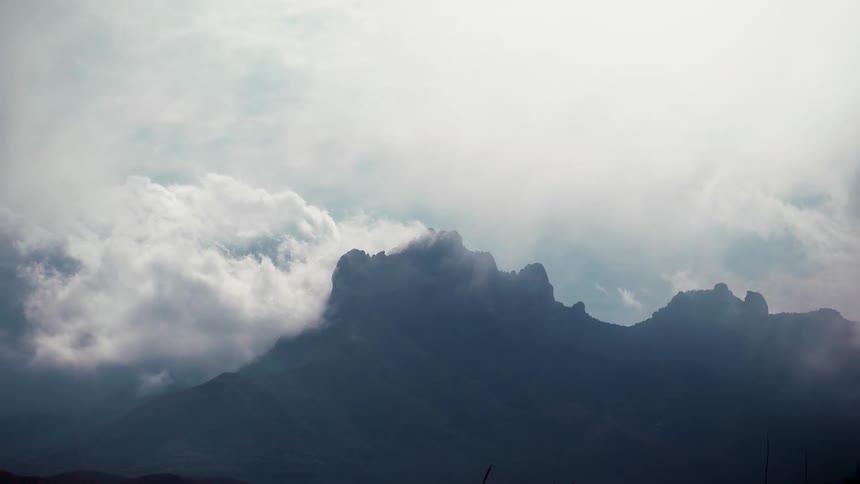 Cloud bank floats toward misty mountain