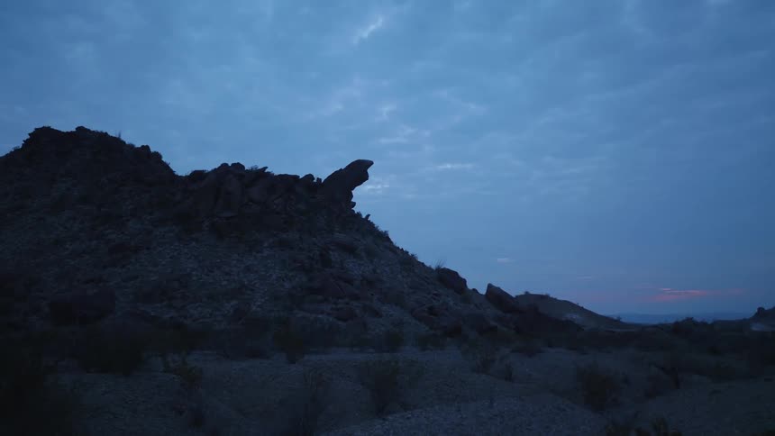 A rocky hill in the badlands under a cloudy sky in the evening