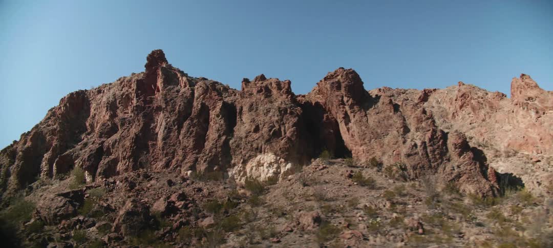 A small mountain looms above a slope covered in scrub bushes