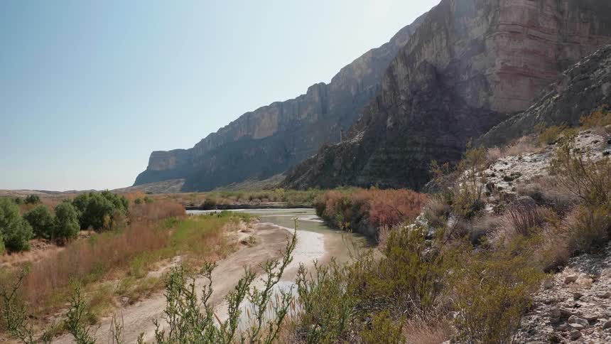 A river bed runs between mountains and brushland