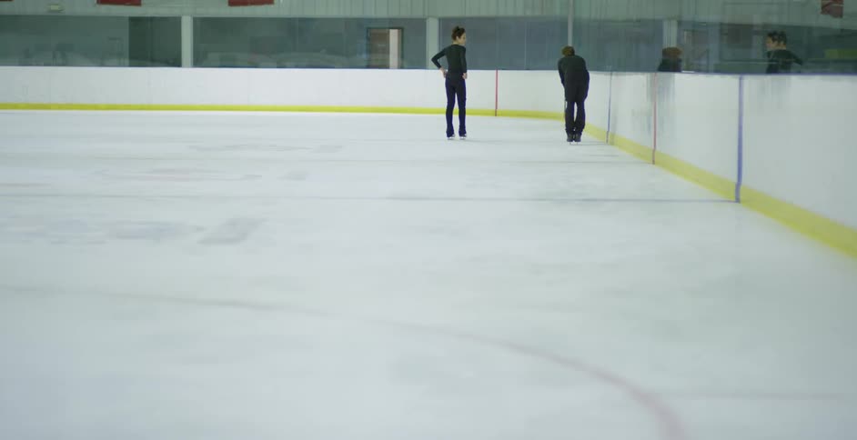 A man and a woman ice skating in an ice skating rink