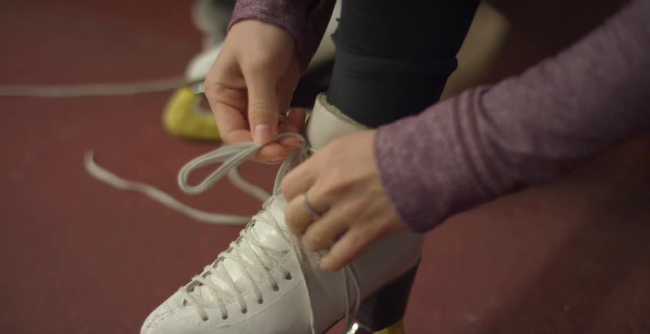 Woman ties shoelaces of ice skates