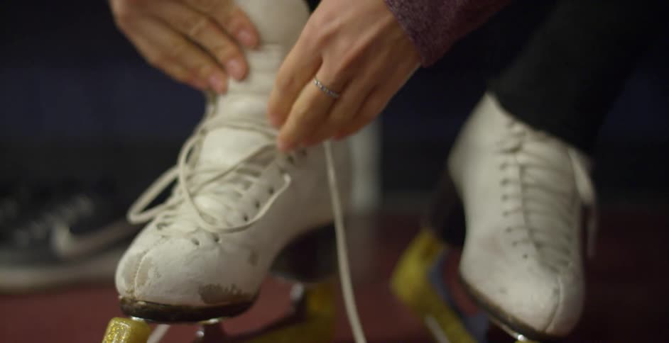 A white woman ties the laces on her ice skates