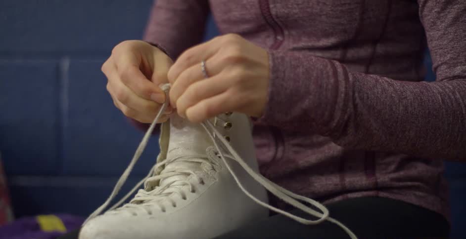 A woman unties a knot in a skate lace