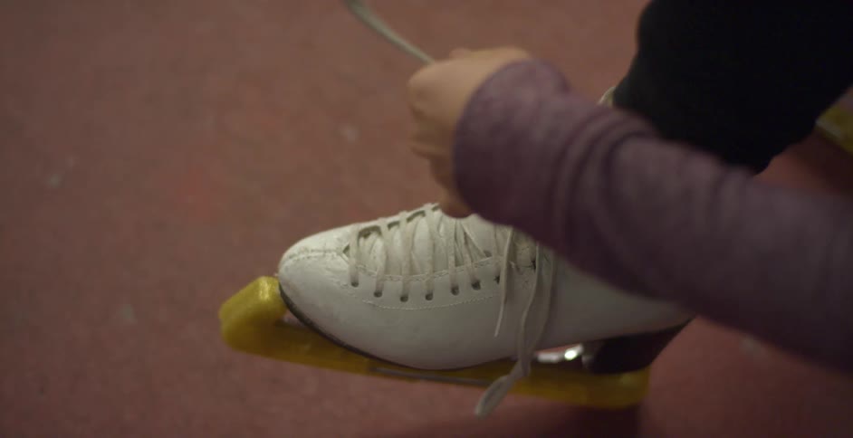 A woman ties her ice skate