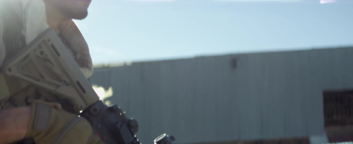 A soldier with a rifle runs through smoke outside a building
