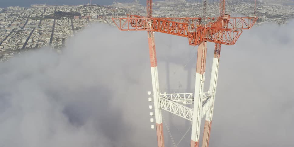 A tall structure stands high above the clouds in a massive sprawling city