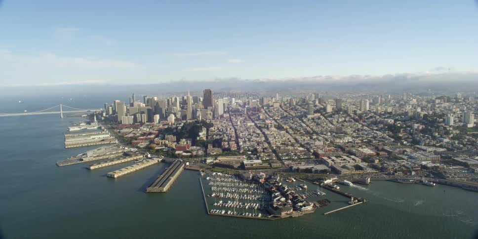 Boats docked in a marina and piers jutting out into the ocean on the waterfront of a city