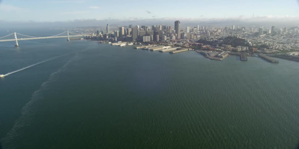 A dense downtown urban area sits on the coast of a bay