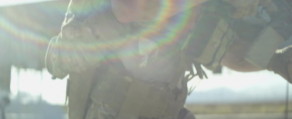 A soldier in camouflage running outdoors while carrying an assault rifle