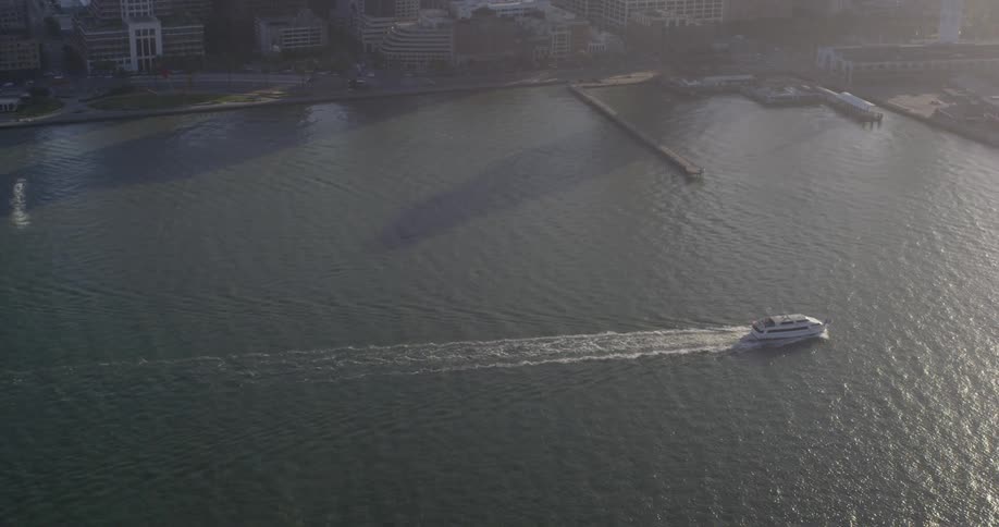 A ship on the ocean next to a coast with buildings