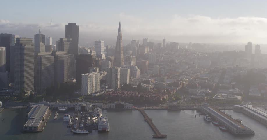 Aerial view of skyscrapers and tall buildings by a river with the skyline in the background