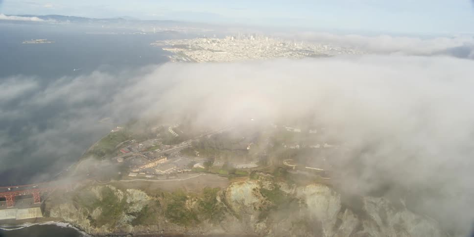 Clouds covering a bridge and the water and a city skyline