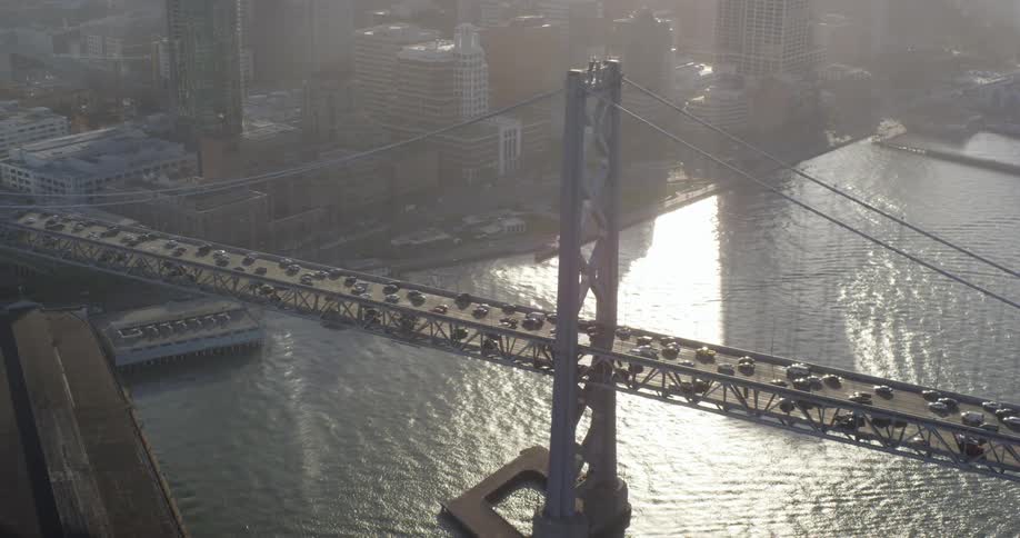 Traffic moves across a suspension bridge into a city