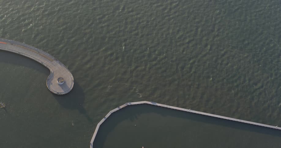 Boats docked in a marina with a barricade and a pedestrian walkway out onto the water