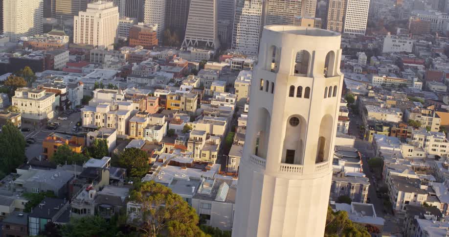 Roof tops and neighborhood buildings in front of towers and skyscrapers in a city on a sunny day