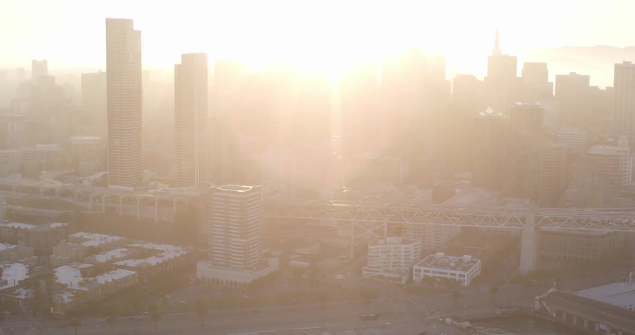 The sun hovers a downtown city skyline