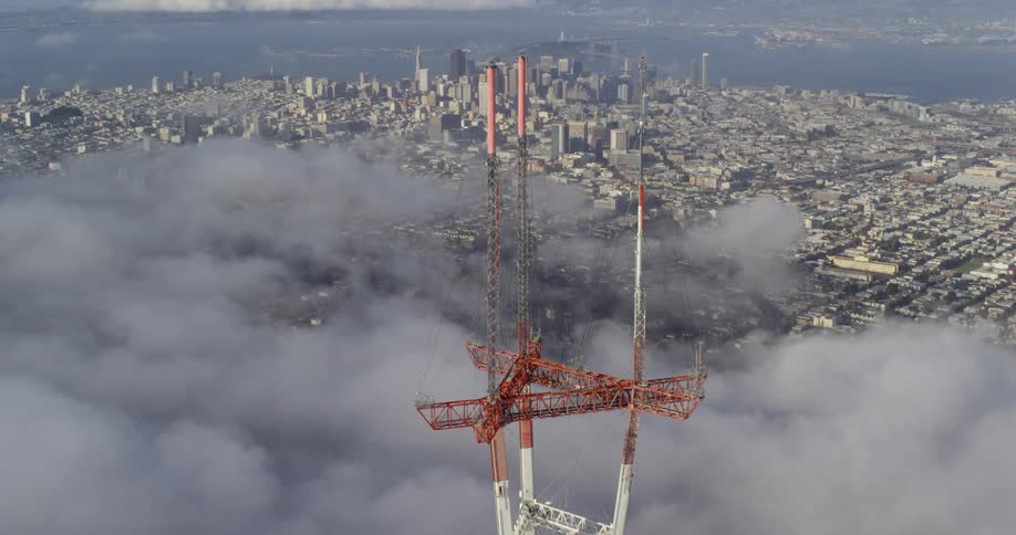 A large metal antenna towers over a distant urban downtown area