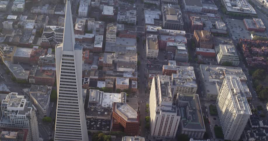 Aerial view of a white skyscraper andtower blocks with city streets at sunset