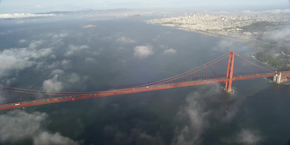 Clouds hang in the air above as cars travel across the golden gate bridge