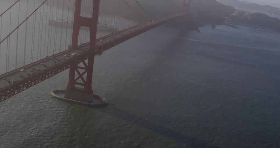 The golden gate bridge with vehicles with ships the ocean and land in the background