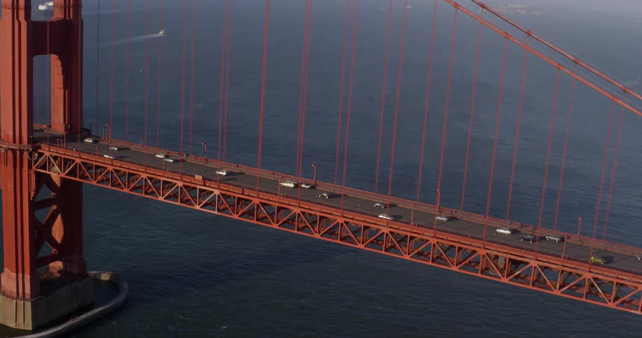 The golden gate bridge with vehicles moving and the ocean in the background