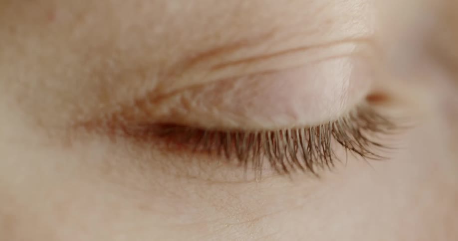 A white persons closed eye moves under an eyelid