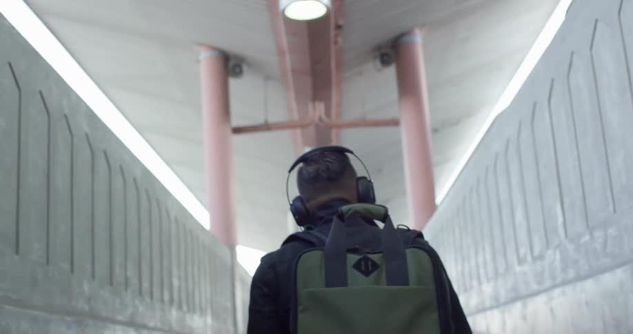 A man walks down a corridor with headphones on