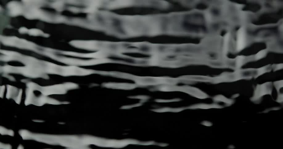 Drops fall on water creating ripples in the surface