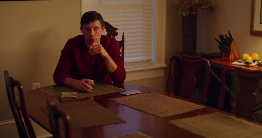 Man sits at dining room table near window smoking