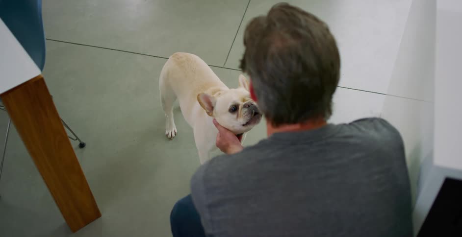 A man is petting his dog in a room