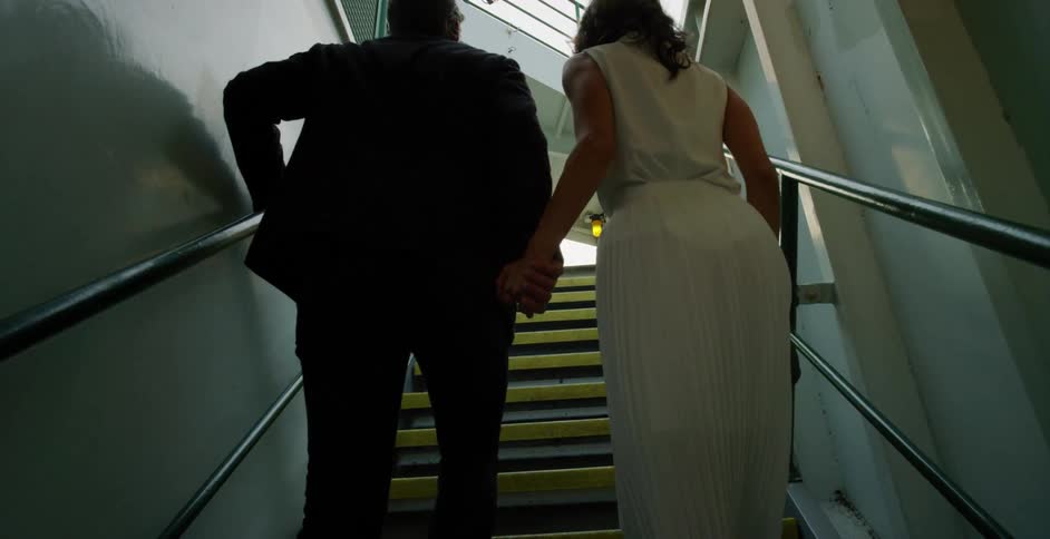 A man and woman walk up a flight of stairs while holding hands